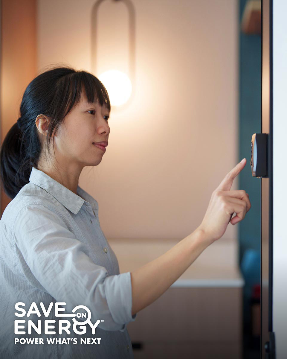 A woman adjusts a smart thermostat