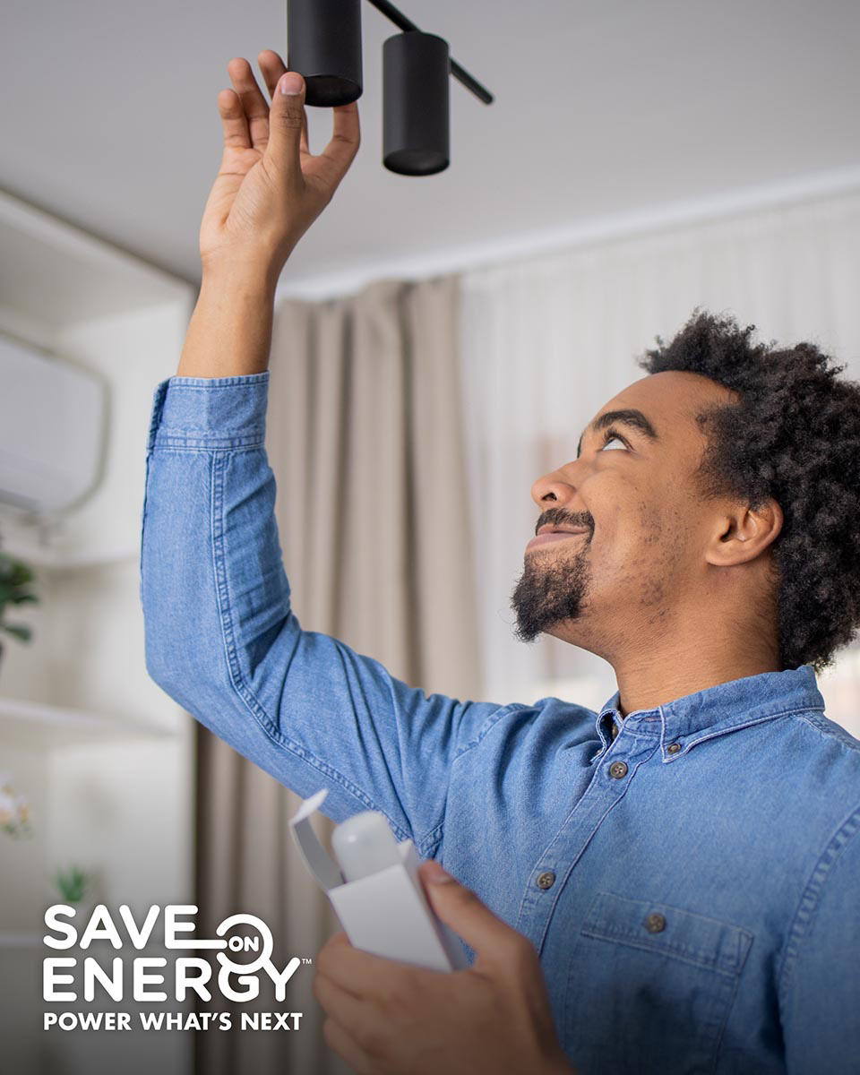 A man replaces a lighbulb in a ceiling light